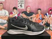 Side profile of a black Nike basketball sneaker with a contrasting white Swoosh and white midsole.