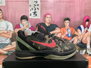 Side view of a camouflage Nike basketball shoe with red side branding, an olive green heel structure, and a light-colored outsole.