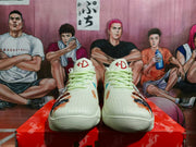 Front view of the cream Nike sneakers showing red tongue branding, pale laces, and multicolor artwork near the toes.