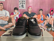 Front view of black lace-up sneakers with textured uppers, orange eyelets, and light-colored outsoles.