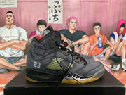 Side view of a grey and black high-top sneaker showing the number 23, mesh panel, circular side detail, cushioning window, and yellow outsole.