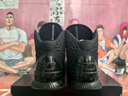 Rear view showing the padded collars, glossy heel panels, and Under Armour branding on the black basketball sneakers.