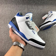 Close-up view of the white, blue, and black high-top sneaker showing the side profile, perforated panels, and lace area.