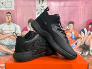 Angled view of the black Nike sneakers showing the side panels, textured forefoot, laces, and outsole.