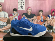 Side view of a blue basketball shoe with a white side logo, black side panel, and white outsole.