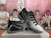 Angled view showing the perforated gray upper, black laces, gold swoosh, and marbled midsole structure.