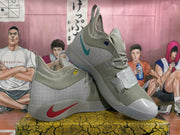 Angled view of the gray Nike basketball sneakers showing contrasting swoosh details, forefoot straps, high-top collars, and textured soles.