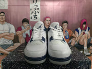 Front view of white high-top sneakers with dark blue tongue branding, mesh panels and structured lace supports.