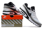 White, black, and grey Nike Air Max sneakers shown with a shoebox; the box label displays a sample size.