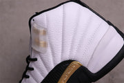 Close-up of the white stitched side panels, black overlays, and gold accent on an Air Jordan 12 sneaker