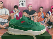 Side view of a green Jordan sneaker showing the textured side panel, red accent detail, embroidered heel graphic, and white midsole.