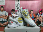 Angled view of a pair of white, gray, and gold Nike basketball sneakers showing the patterned side panels, red accents, and thick midsoles.