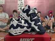Three-quarter view of the white and dark blue Nike sneakers displayed together, showing the side panels and outsole details.