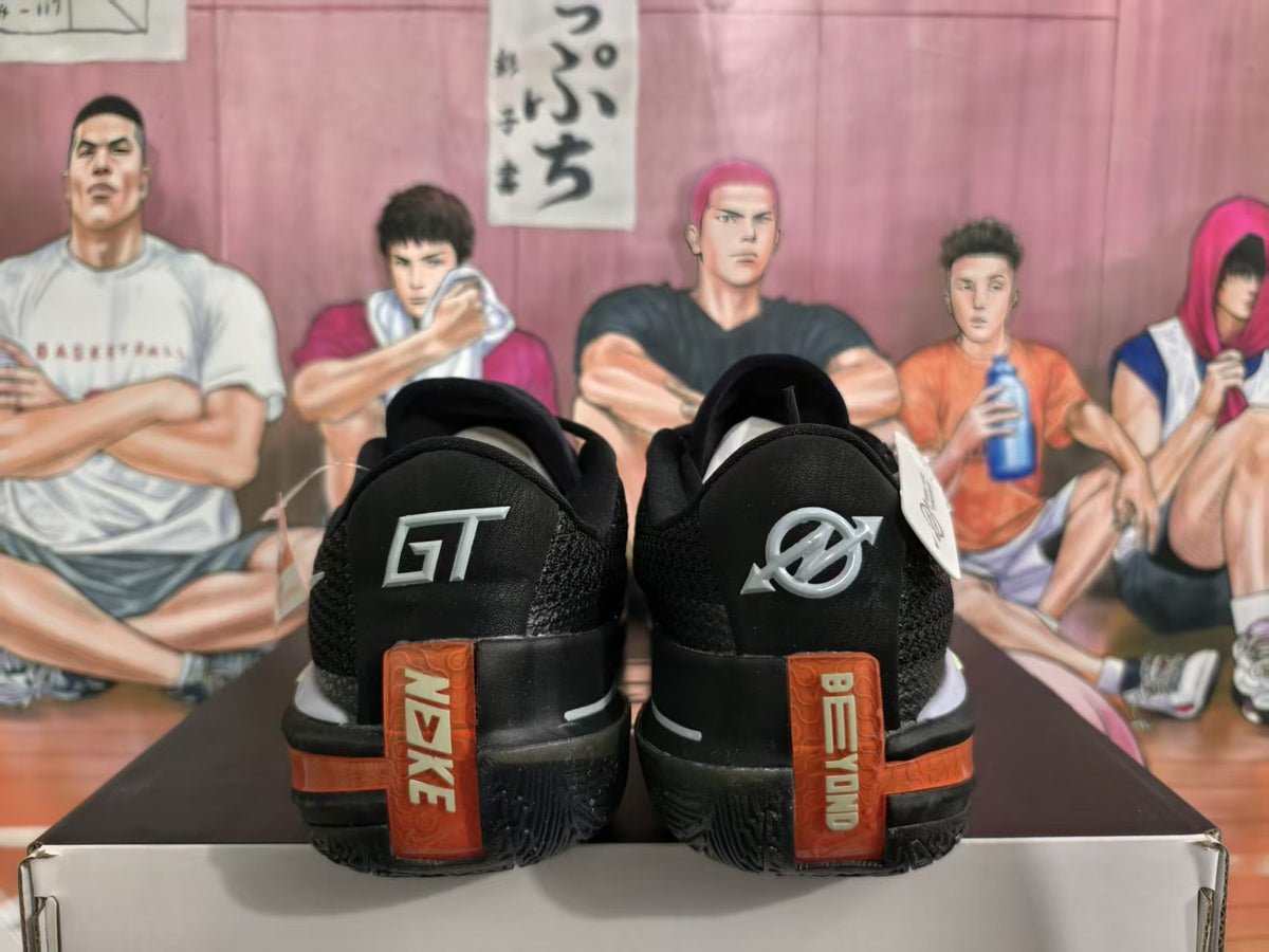 Rear view of black basketball sneakers with red heel panels, contrasting branding, and a textured outsole.