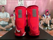 Rear view of the red basketball sneakers showing green heel striping, Kobe branding, and white heel accents.
