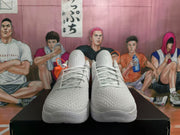 Front view of white Nike basketball sneakers with textured uppers, laces, Kobe tongue emblems, and orange lace accessories.