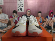 Front view of white Nike running shoes with black Swooshes and coral toe and sole accents.