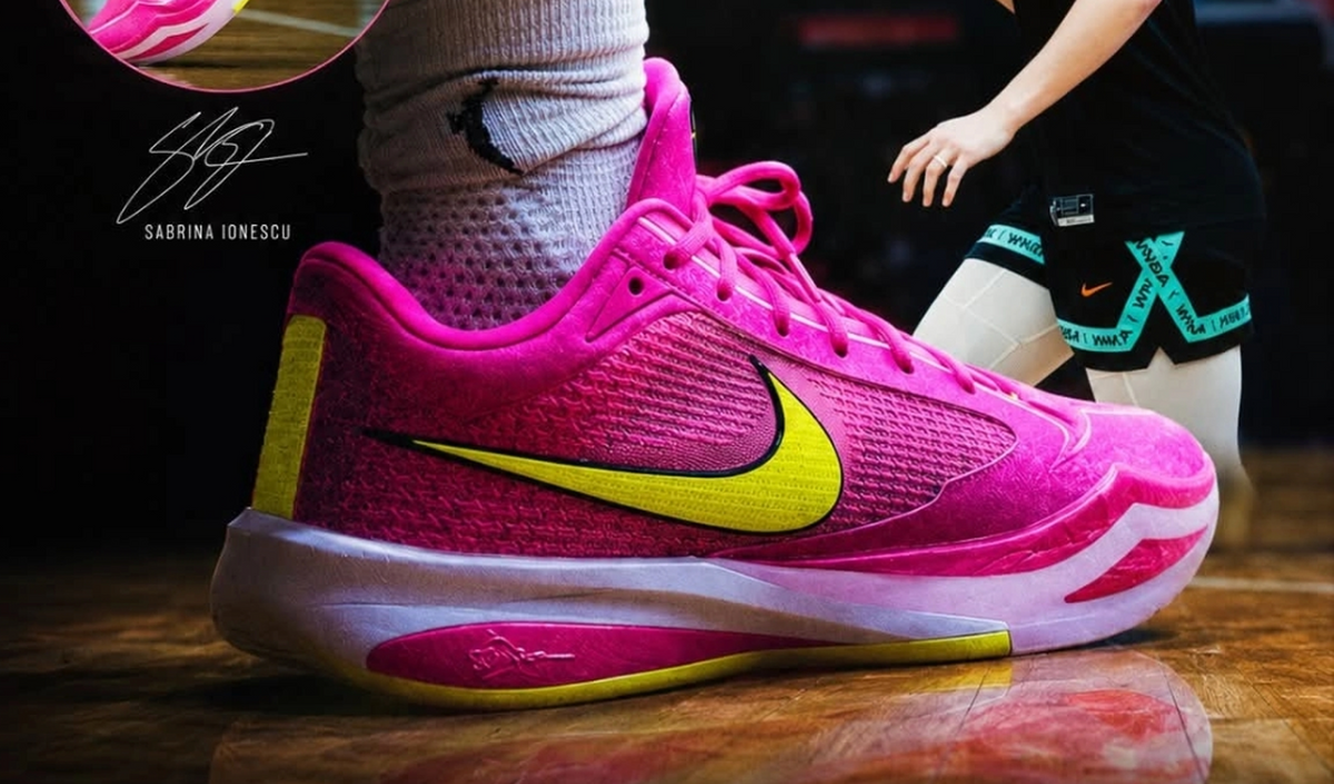 Pink Nike basketball sneaker with a yellow Swoosh, layered pink-and-white outsole, and Sabrina Ionescu branding.