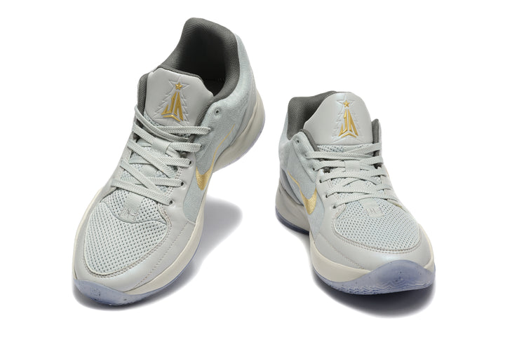 Pair of light gray Nike Kyrie basketball shoes with gold accents, shown from the front