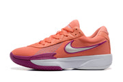 Side profile of a coral Nike basketball sneaker with a white Swoosh-style mark outlined in purple and Air Zoom text near the forefoot.