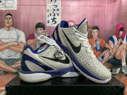 Angled view of the white and purple Nike basketball shoes, showing their textured uppers and contrasting side and heel details.