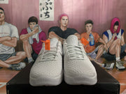 Front view of white and gray basketball sneakers showing the laces, textured toe areas, padded tongues, and tongue emblems.