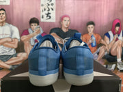 Rear view of a pair of blue sneakers showing textured heel panels, pull tabs, and translucent off-white soles.