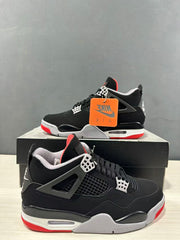 Close side view of the black Jordan Air Jordan 4 sneaker showing mesh panels, lace supports, and layered sole details.