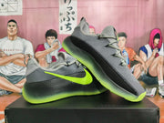 Angled view of gray Nike basketball shoes with black side panels and green detailing.