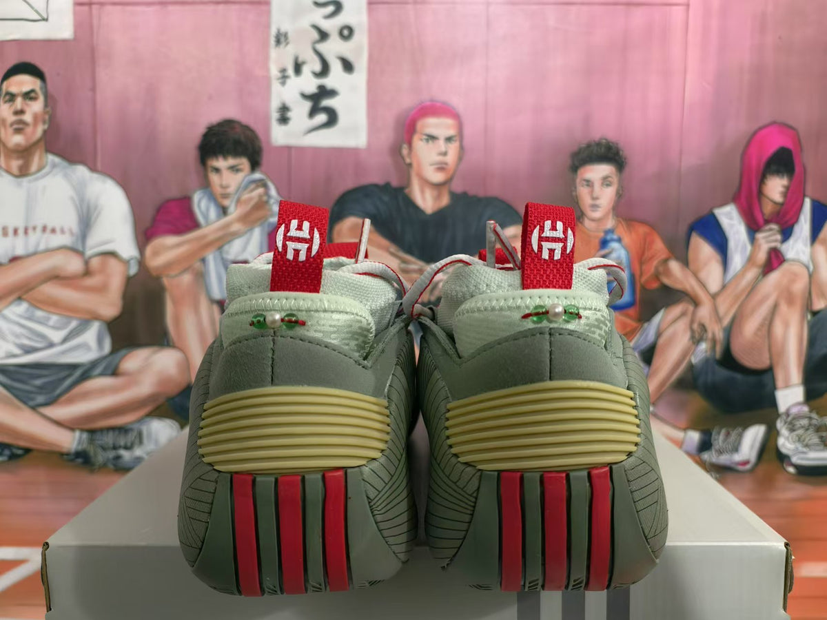 Rear view of green sneakers with red pull tabs, cream midsoles, and layered heel details on a shoebox.