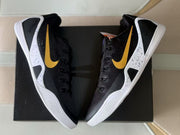 Top-down view of the black and gold sneakers arranged over a black shoebox.