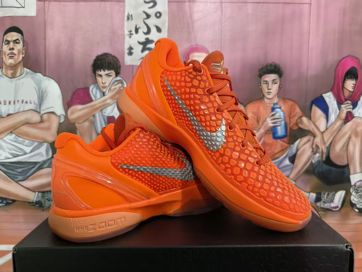 Pair of bright orange Nike Zoom basketball sneakers displayed on a black box, showing the textured upper, silver Swoosh, and sculpted sole.