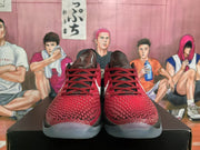 Front view of the black and red sneakers showing textured red uppers, red laces, white branding, and translucent outsoles.