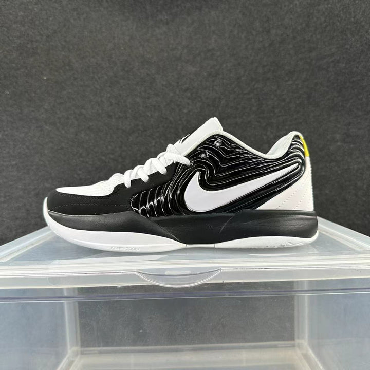 Side view of a black and white Nike low-top basketball shoe with a large white Swoosh and a small yellow heel accent.