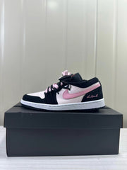 Black, pale pink, and white low-top sneaker shown in profile on a box