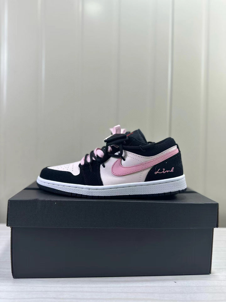 Black, pale pink, and white low-top sneaker shown in profile on a box