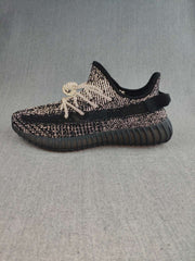 Side profile of a black Yeezy 350 V2-style sneaker with a dark ribbed sole.
