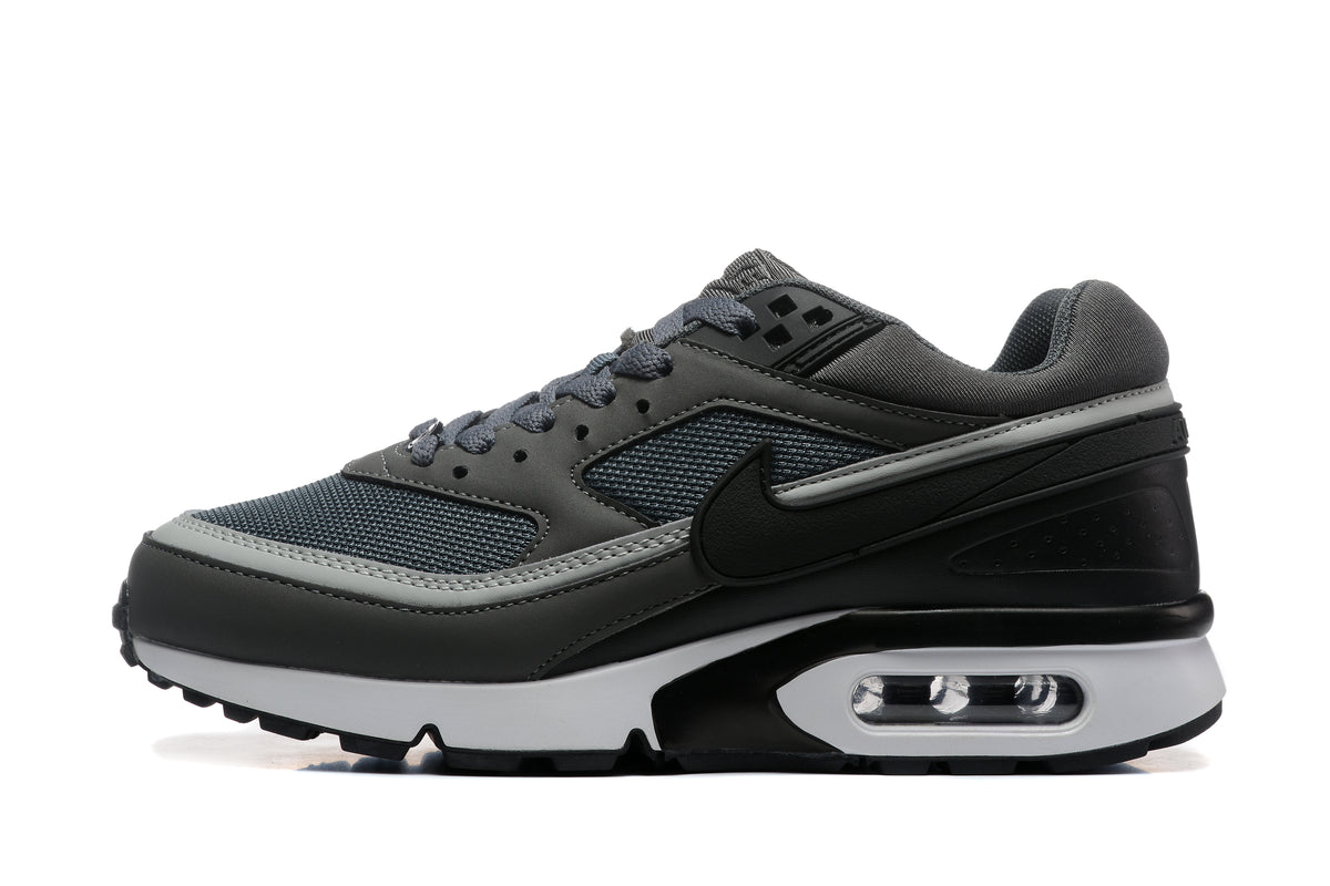 Side view of a dark gray Nike sneaker with mesh panels, a black Swoosh, and a visible heel Air unit.