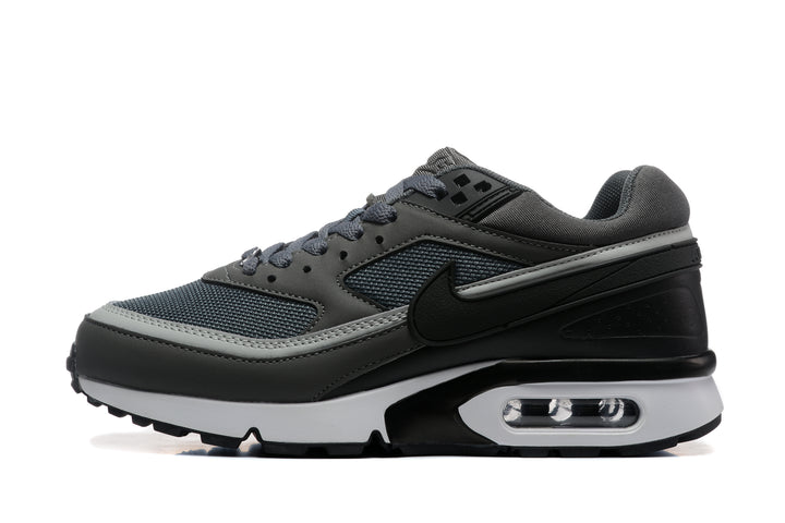 Side view of a dark gray Nike sneaker with mesh panels, a black Swoosh, and a visible heel Air unit.