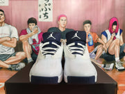 Front view of white Jordan shoes showing navy tongues and lace-up fronts.