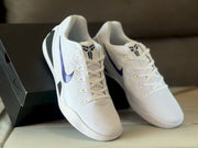 Pair of white Nike Kobe 9 sneakers displayed from above, showing the tongue logos, laces and purple side accents.