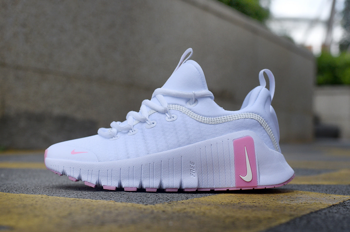Side view of a white Nike Free sneaker with pink accents and a grooved sole.