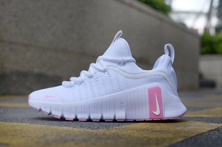 Side view of a white Nike Free sneaker with pink accents and a grooved sole.