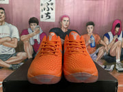 Front view of the orange sneakers showing the textured toe boxes, orange laces, tongue details, and translucent outsole sections.