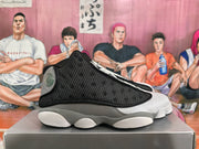 Side profile showing the perforated black upper, grey overlays, white midsole sections, and black outsole.