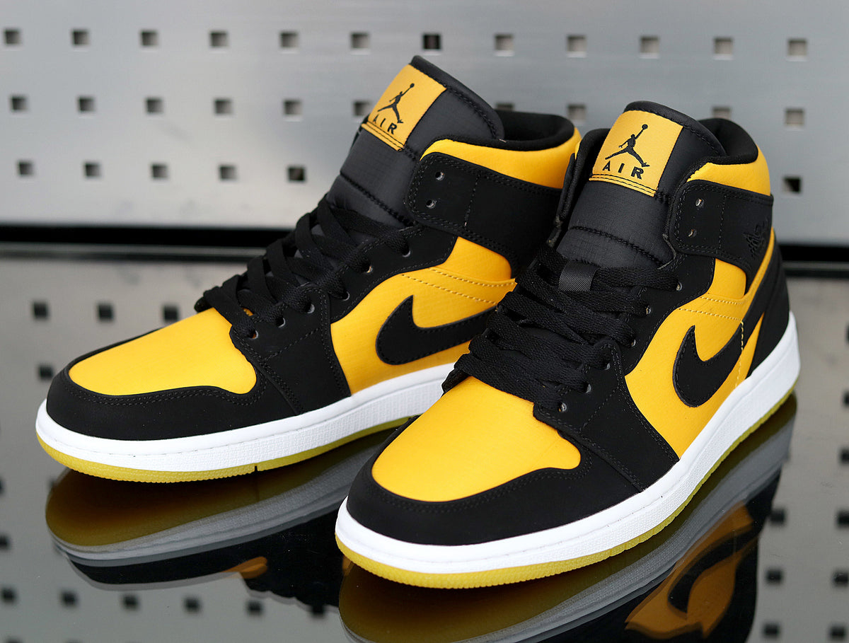 Pair of yellow and black Jordan high-top sneakers shown from a front three-quarter angle with white midsoles and yellow outsoles.
