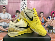 Pair of yellow and cream basketball shoes with black Nike swooshes displayed on a black box.