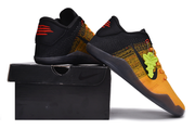 Black and yellow-orange basketball shoes displayed on and beside a black box