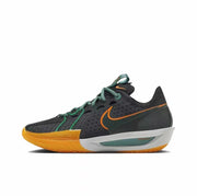 Side view of a black Nike GT Cut 3 sneaker with green laces, orange Swoosh detailing, and a gum-colored outsole.