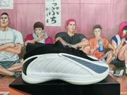 Side view of a white basketball shoe with a black upper section and blue-gray side accents.